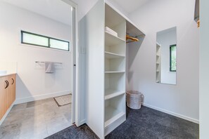 A modern bathroom with a shower, a towel rack, a window, and a built-in storage unit with shelves.