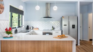 A modern kitchen with a central island, stainless steel appliances, and pendant lighting.