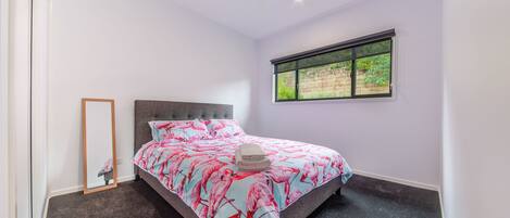 Un dormitorio con cama, ventana, ventilador de techo y espejo.