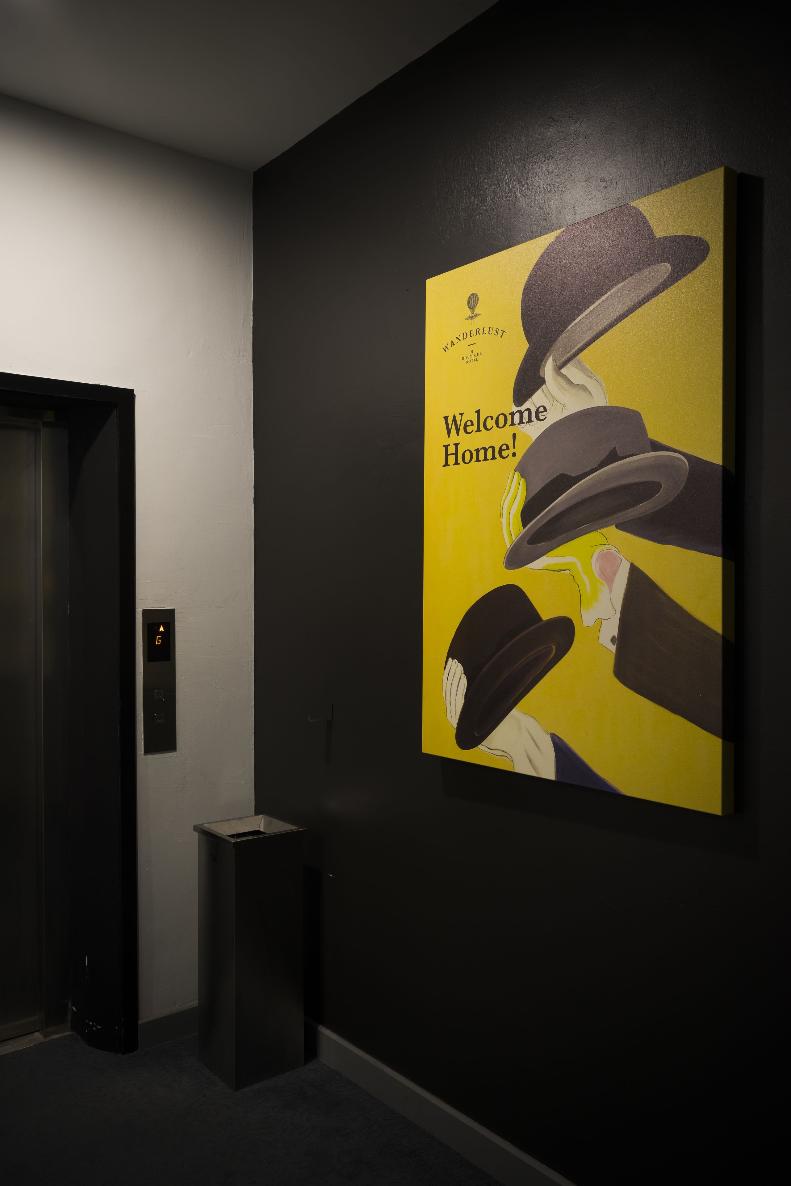 A hallway with a wall-mounted poster featuring a hat and the text "Welcome Home!".