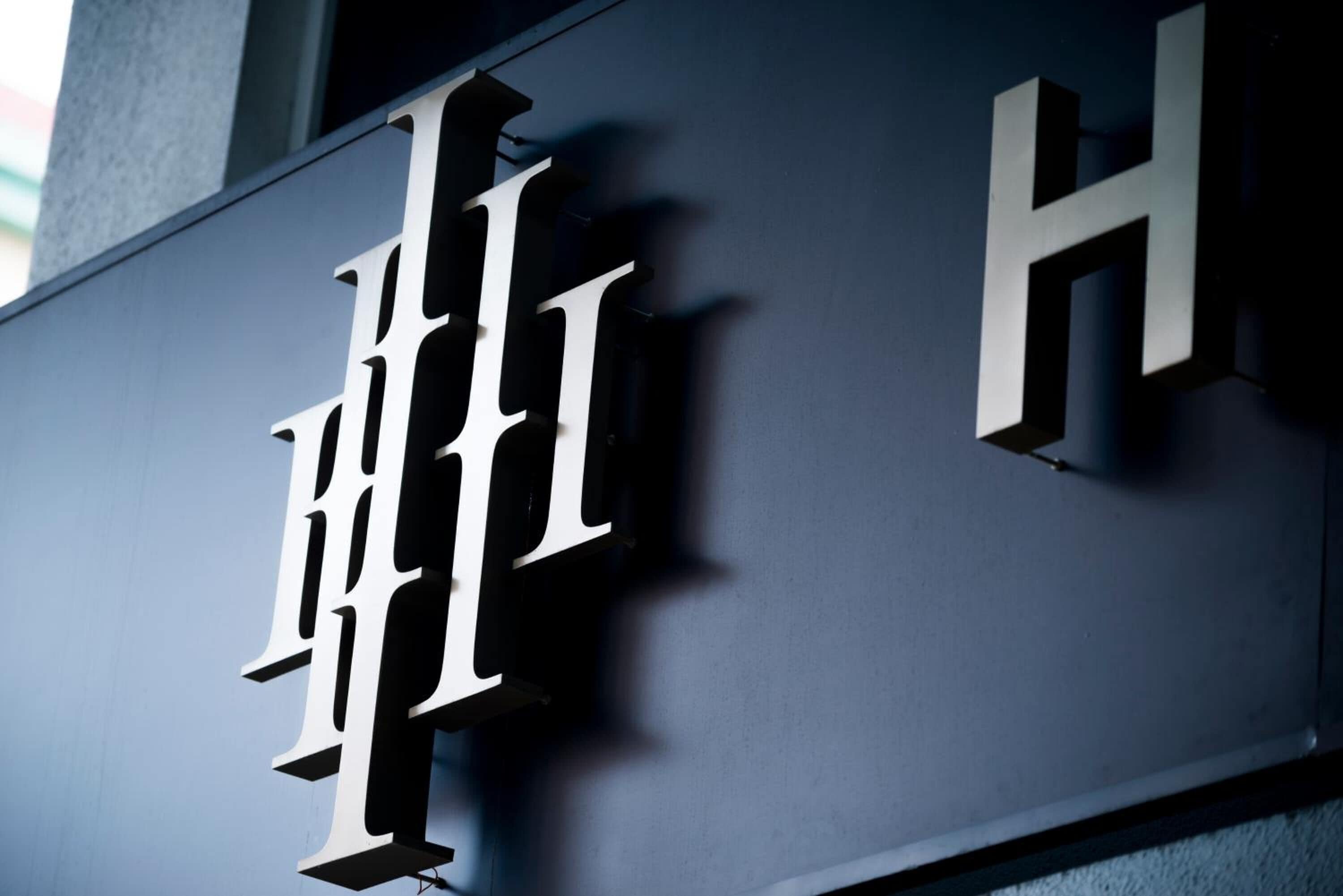 Une grande lettre « H » blanche et bien visible, sur un fond sombre, qui fait probablement partie de l’enseigne d’un bâtiment.