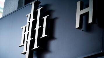 Une grande lettre « H » blanche et bien visible, sur un fond sombre, qui fait probablement partie de l’enseigne d’un bâtiment.