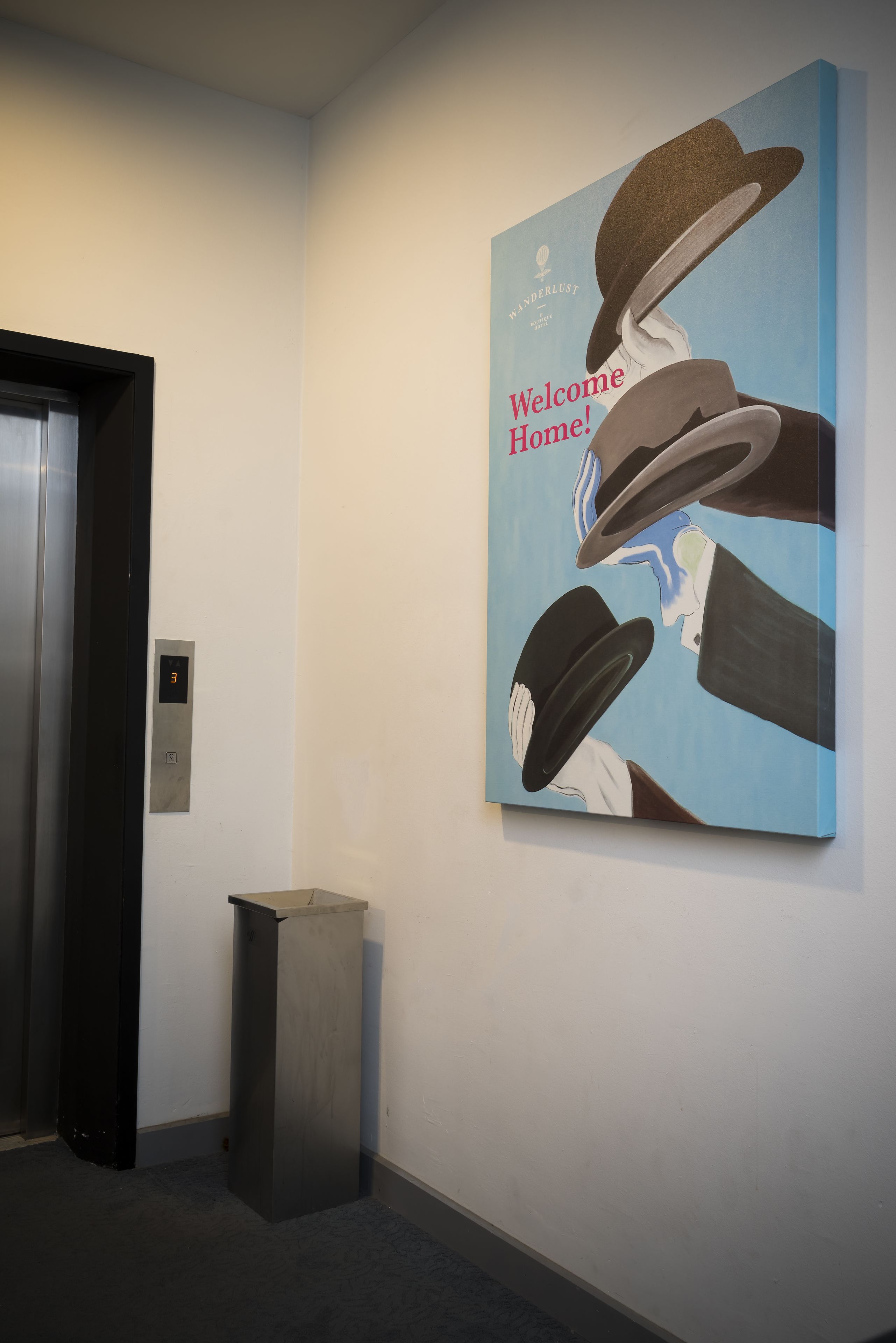 A hallway with a wall-mounted artwork depicting a man in a hat and a woman in a dress, with the text "Welcome Home!" visible.