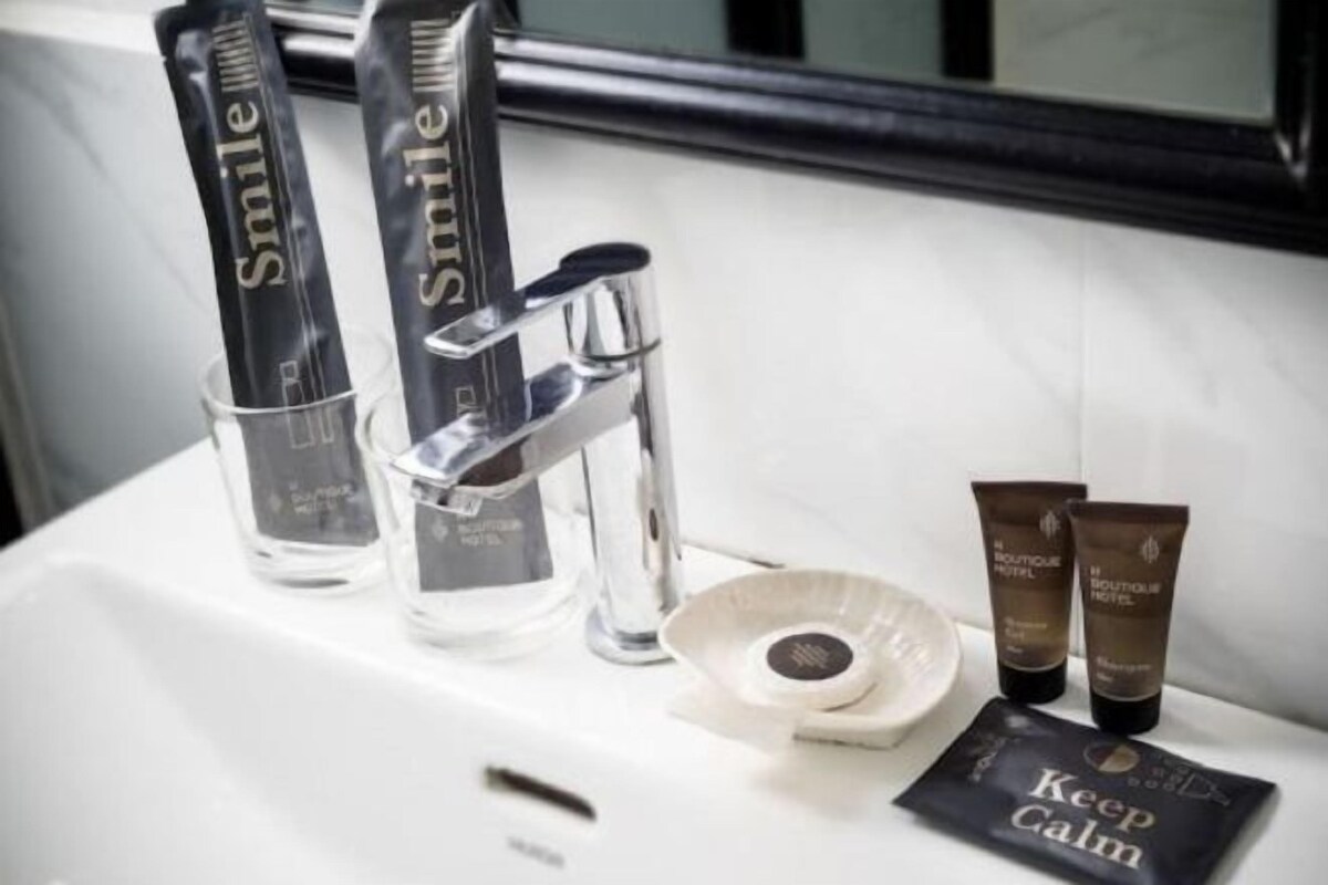 A bathroom sink with a mirror, a toothbrush holder, and two tubes of lotion.