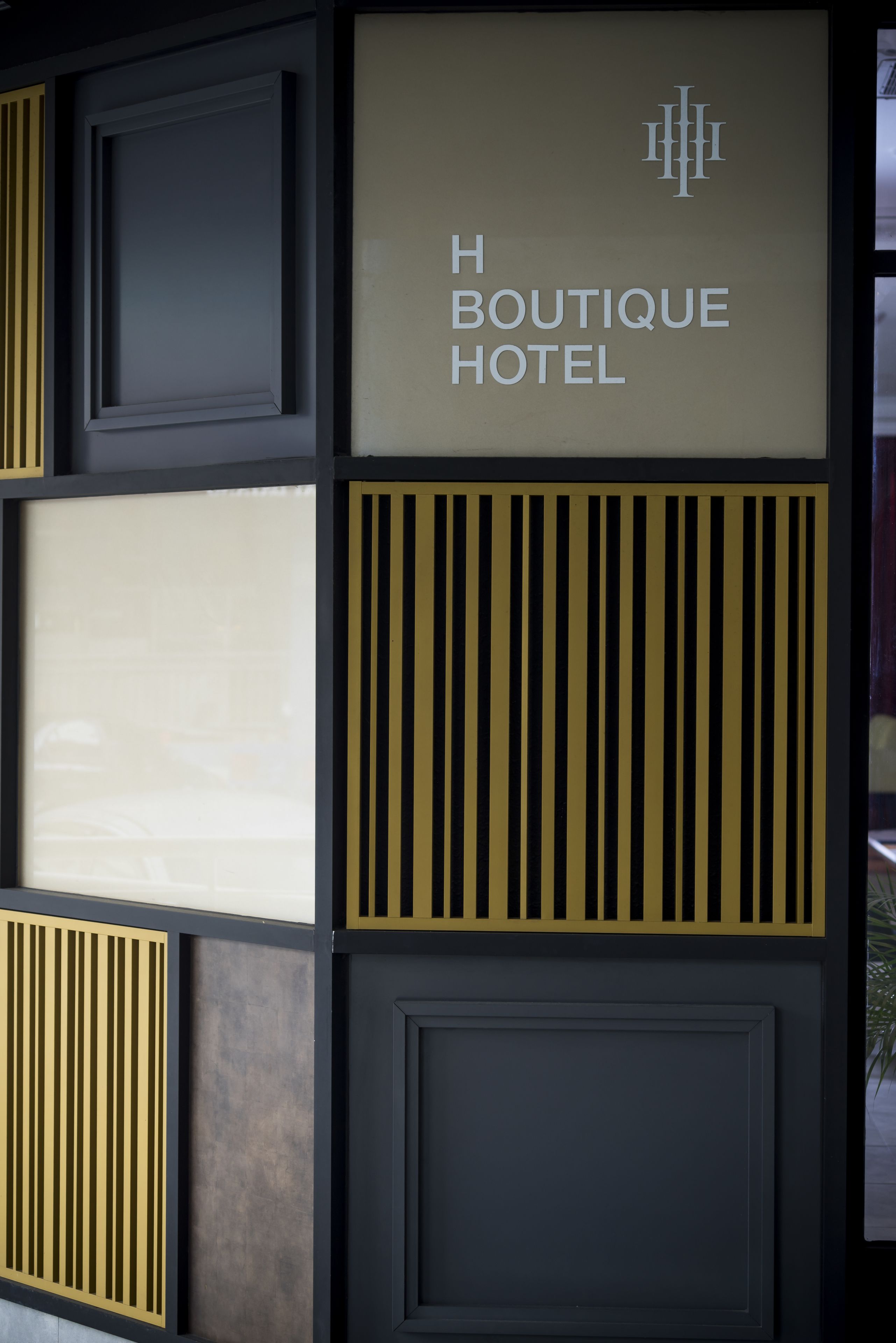 Un mur sur lequel est affiché un panneau indiquant « H Boutique Hotel » et sur lequel figure également un logo.