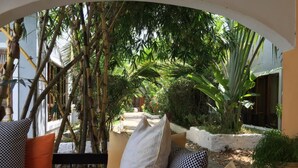 A cozy outdoor seating area with a red and yellow sofa, white and black checkered cushions, and a potted plant. - Ritam Getaways (Tiwi)