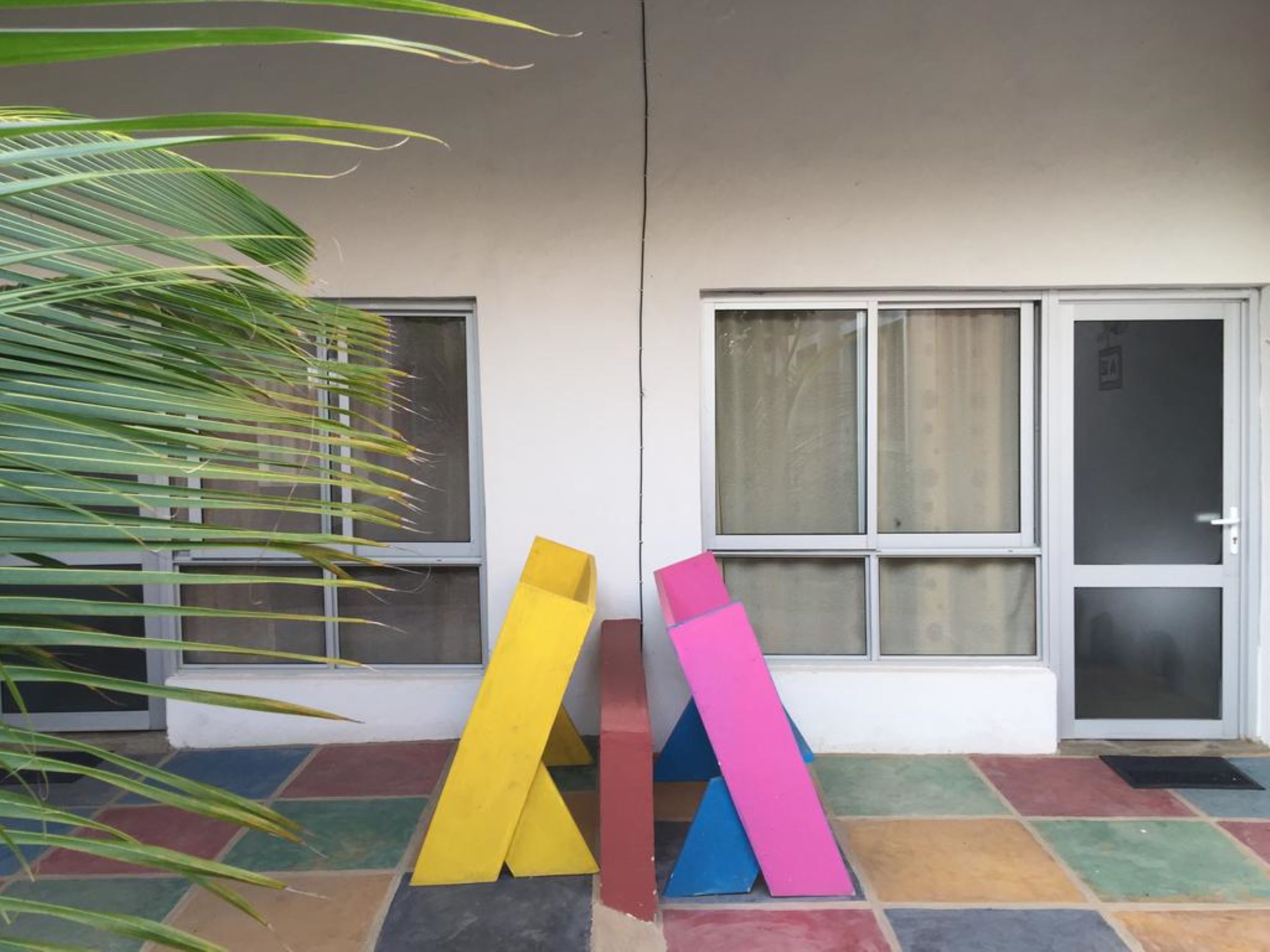 Fachada de edificio con grandes ventanales y suelo de baldosas.