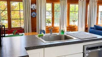 A kitchen with a central island, a dishwasher, a stove, and a ceiling fan.