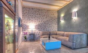 Ein Weinkeller mit Steinwand, Ledersofa, Couchtisch und zwei Wandleuchten.