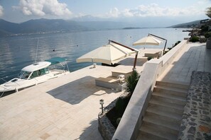 Une terrasse au bord de l’eau, avec un quai pour bateaux, des sièges extérieurs et un escalier en pierre menant vers le bas.