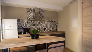 A compact kitchen with a wooden countertop, a built-in stove, a sink, and a potted plant.