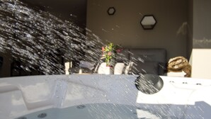 A hot tub with water jets spraying upwards, surrounded by a seating area with a couch and a small table.
