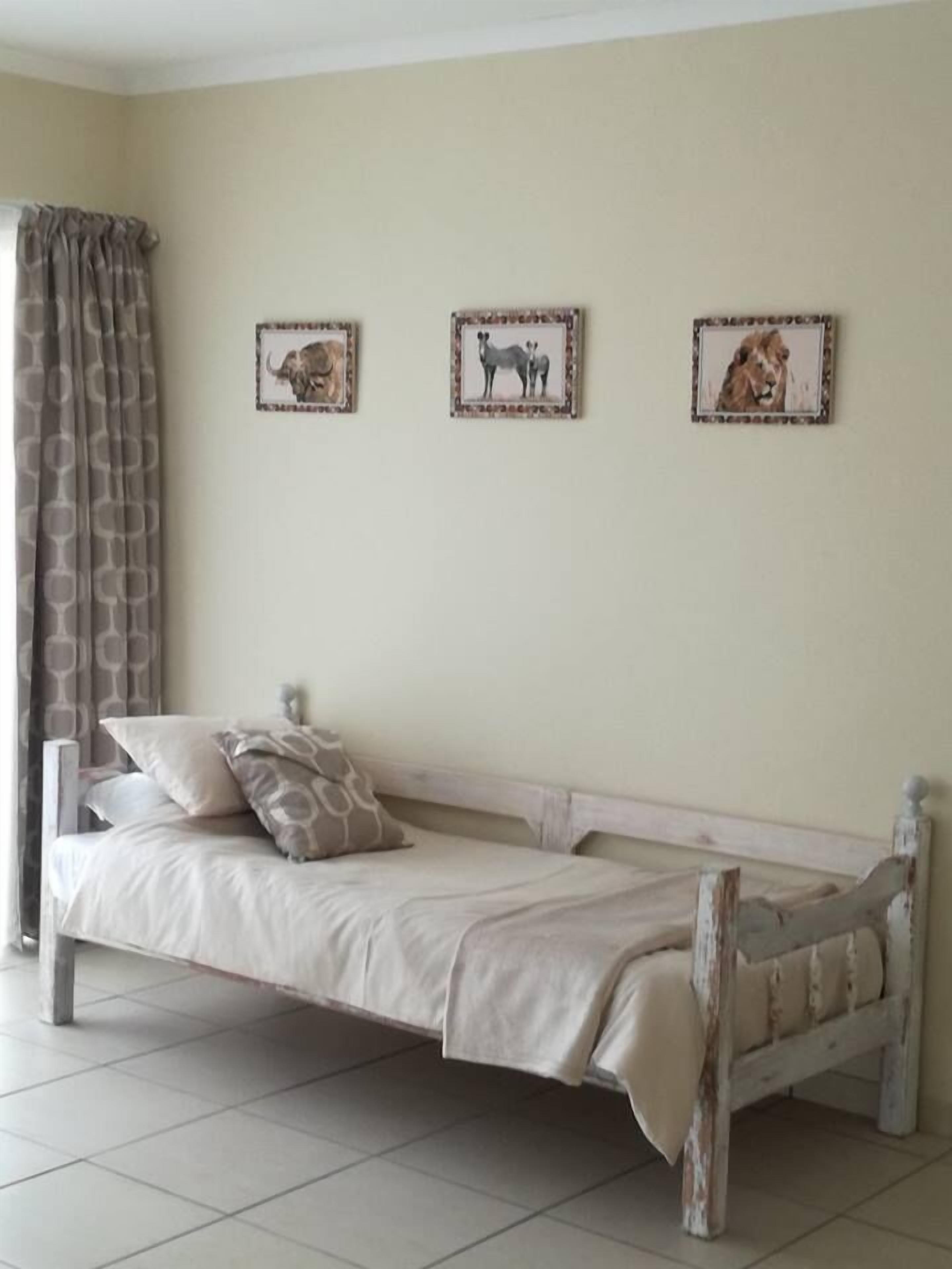A room with a bed, a curtain, and three framed pictures on the wall.