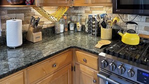 A kitchen with wooden cabinets, a granite countertop, a yellow kettle, and a stove. - 4 Mi to Sugarbush Resort: Waitsfield Retreat (Waitsfield)