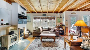 A cozy living room with a wooden ceiling, a fireplace, a sofa, a coffee table, and a lamp. - 4 Mi to Sugarbush Resort: Waitsfield Retreat (Waitsfield)