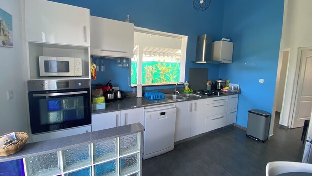 A modern kitchen with white cabinets, a microwave, an oven, a sink, and a window with a view of greenery.