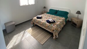 A bedroom with a bed, a nightstand, a lamp, a window, and a ceiling fan.