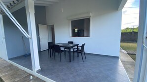 An open patio with a table and chairs, a door, and a window.