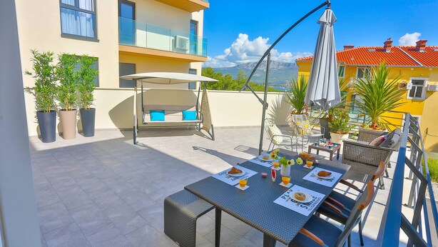 A rooftop terrace with a dining table set for two, outdoor furniture, potted plants, and a view of the cityscape. - Split Luxury Collection (Split)
