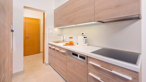 A modern kitchen with wooden cabinets, a built-in dishwasher, and a stainless steel sink. - Split Luxury Collection (Split)