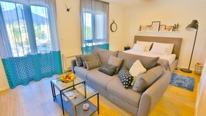 A modern living room with a grey sofa, a glass coffee table, and a bed with a headboard. - Split Luxury Collection (Split)