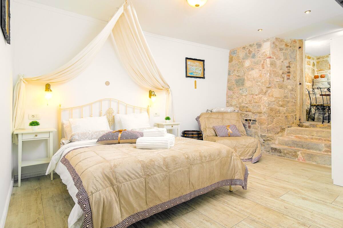 Un dormitorio con una cama grande, una mesita de noche y una pared de piedra.