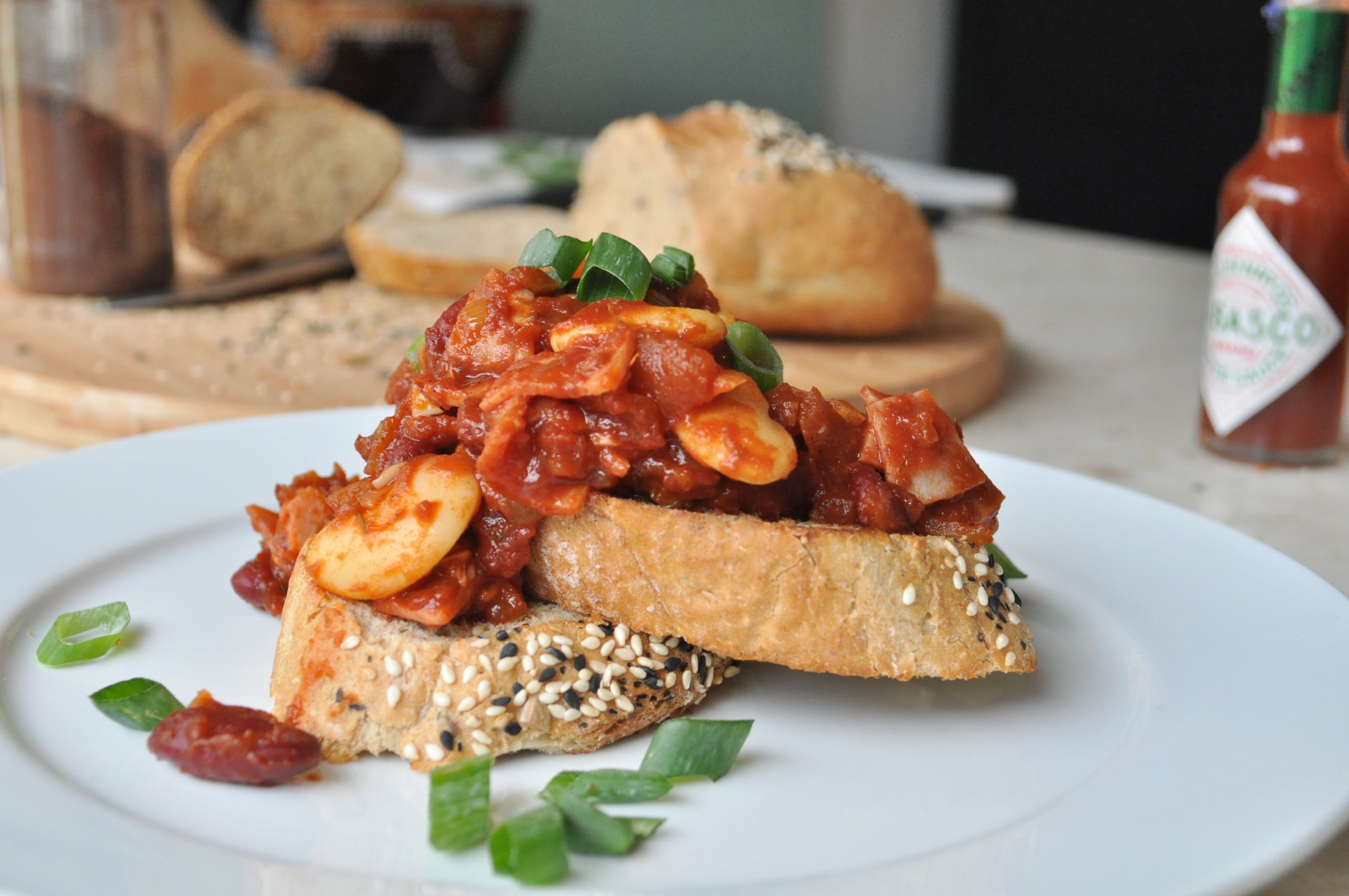 Ein Teller Bruschetta mit Tomatensauce und Mozzarella, garniert mit grünen Zwiebeln, auf einem weißen Teller.