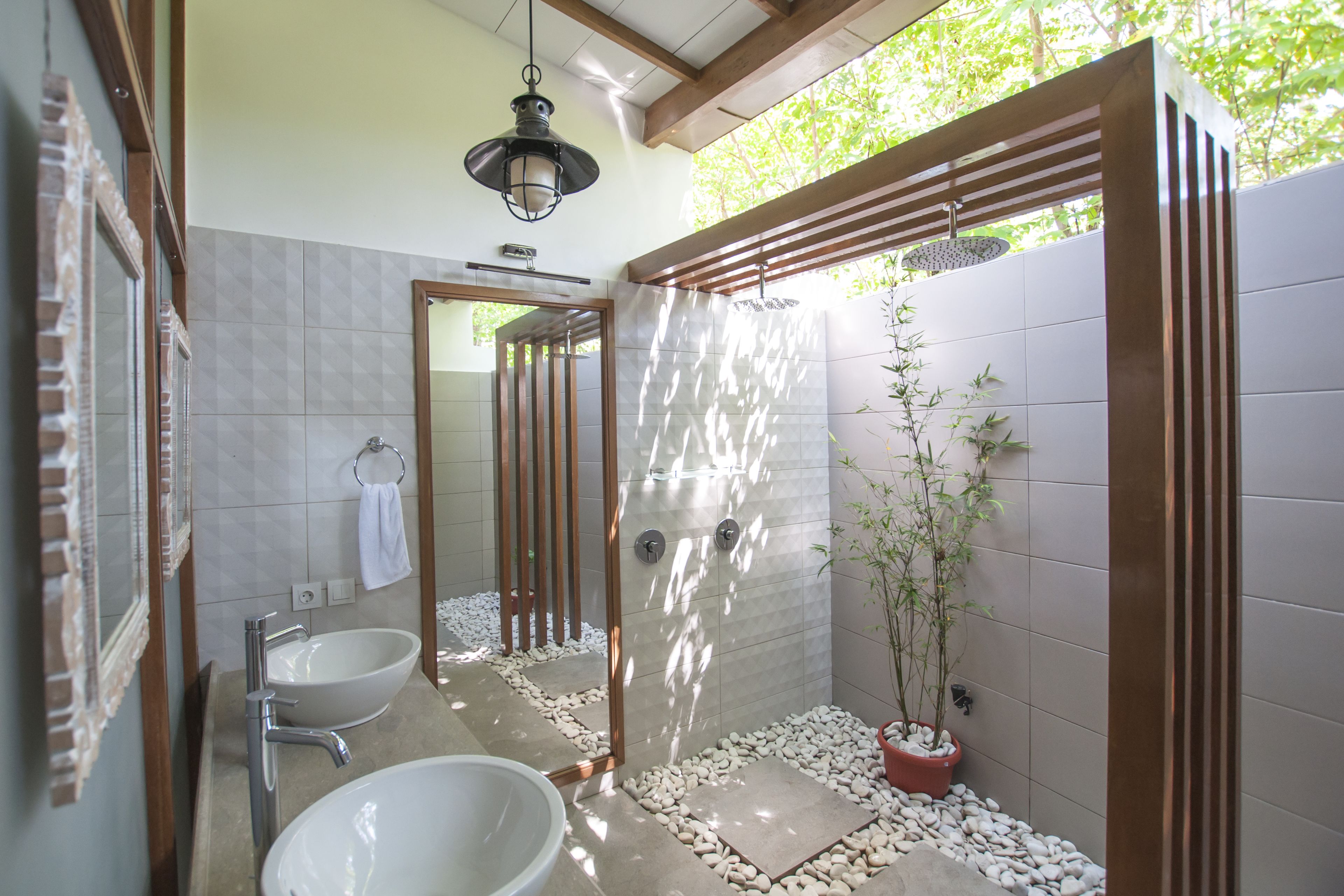 A modern bathroom with a bathtub, two sinks, a shower area, and a potted plant.