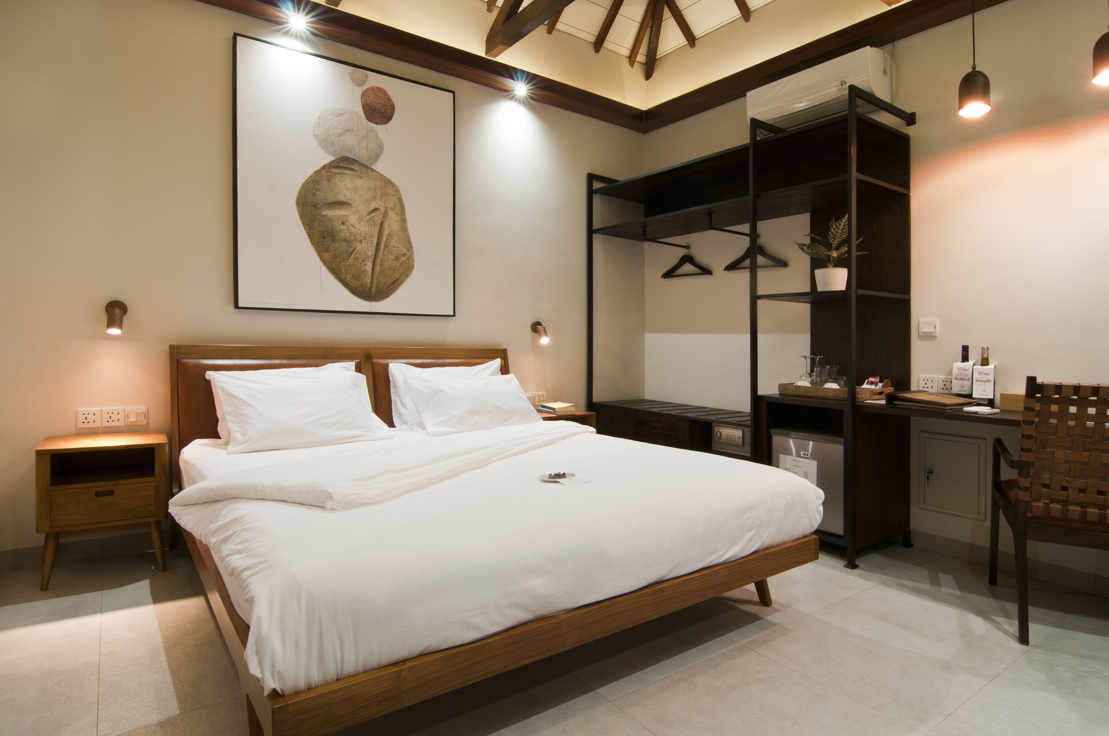 A bedroom with a wooden bed, a desk with a chair, and a hanging plant.