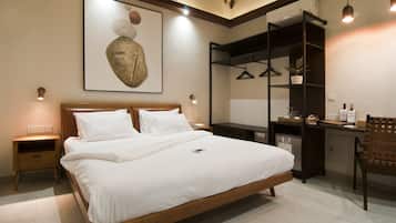 A bedroom with a wooden bed, a desk with a chair, and a hanging plant.