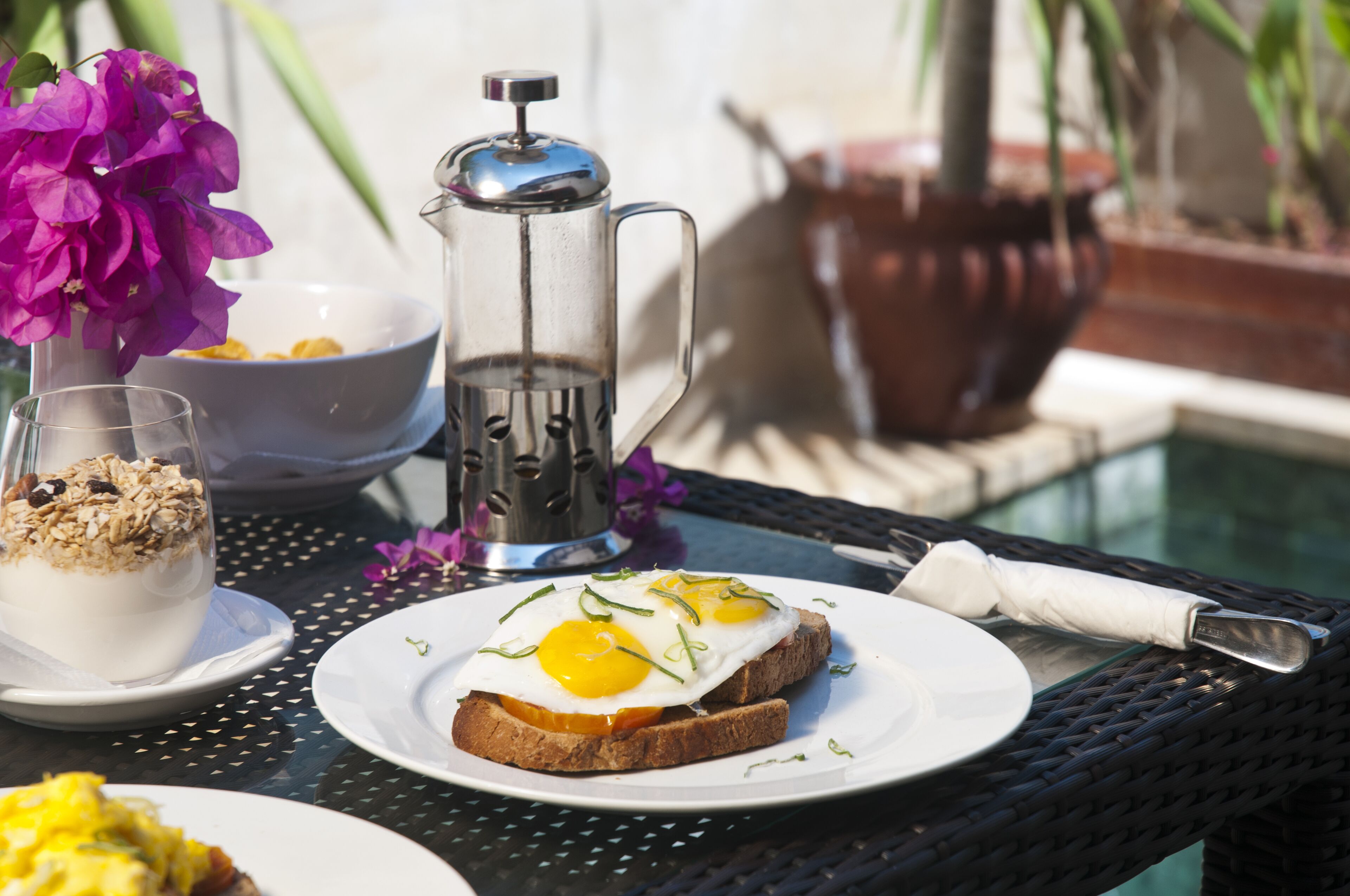 A breakfast setting with toast, eggs, and yogurt parfait on a table.