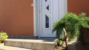 Ein Gebäude mit einer weißen Tür, einem kleinen Fenster und einer Treppe aus Stein, die zum Eingang führt.