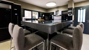 A modern kitchen with a central island, bar stools, and built-in appliances. - Villa Daniela (Eilat)