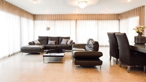 A spacious living room with a sectional sofa, a coffee table, and a dining area with chairs. - Villa Daniela (Eilat)
