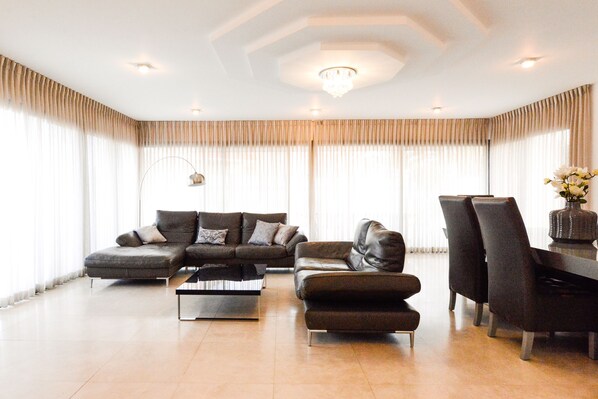 A spacious living room with a sectional sofa, a coffee table, and a dining area with chairs.