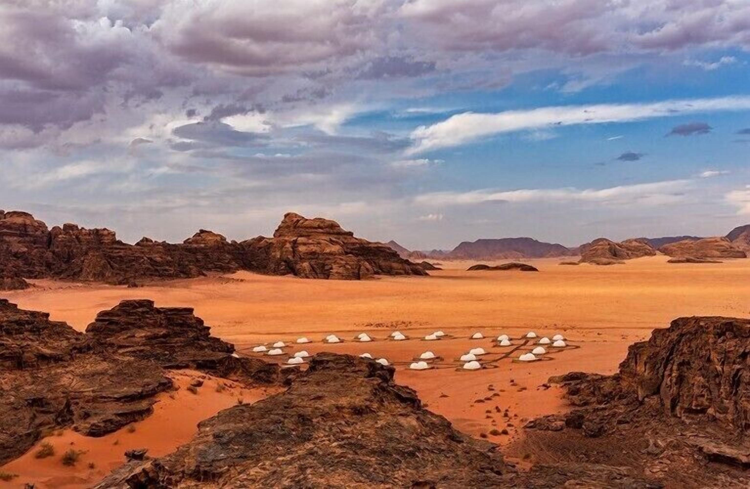 A desert landscape with rock formations and tents.