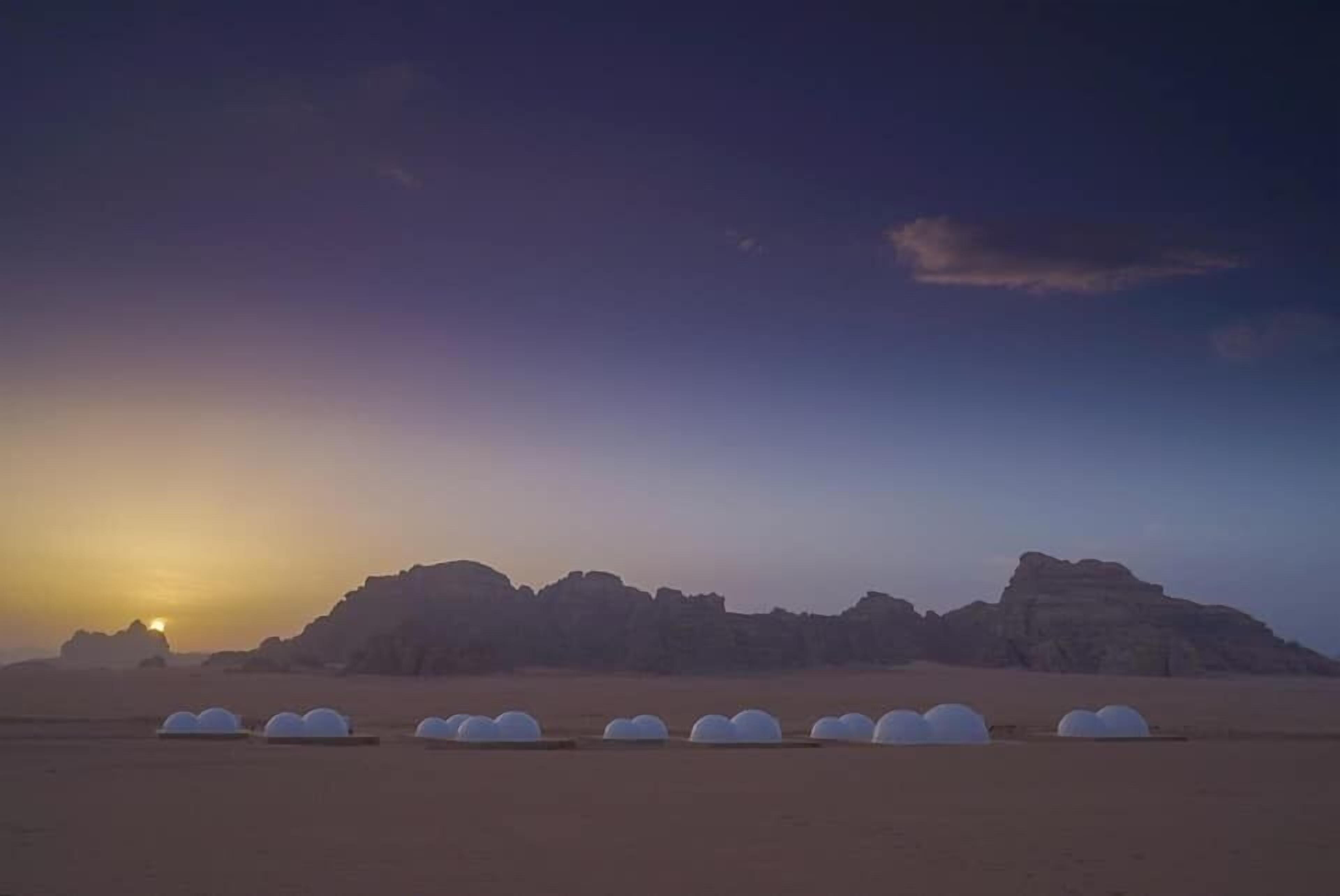 A desert landscape with rock formations and spherical structures in the foreground.