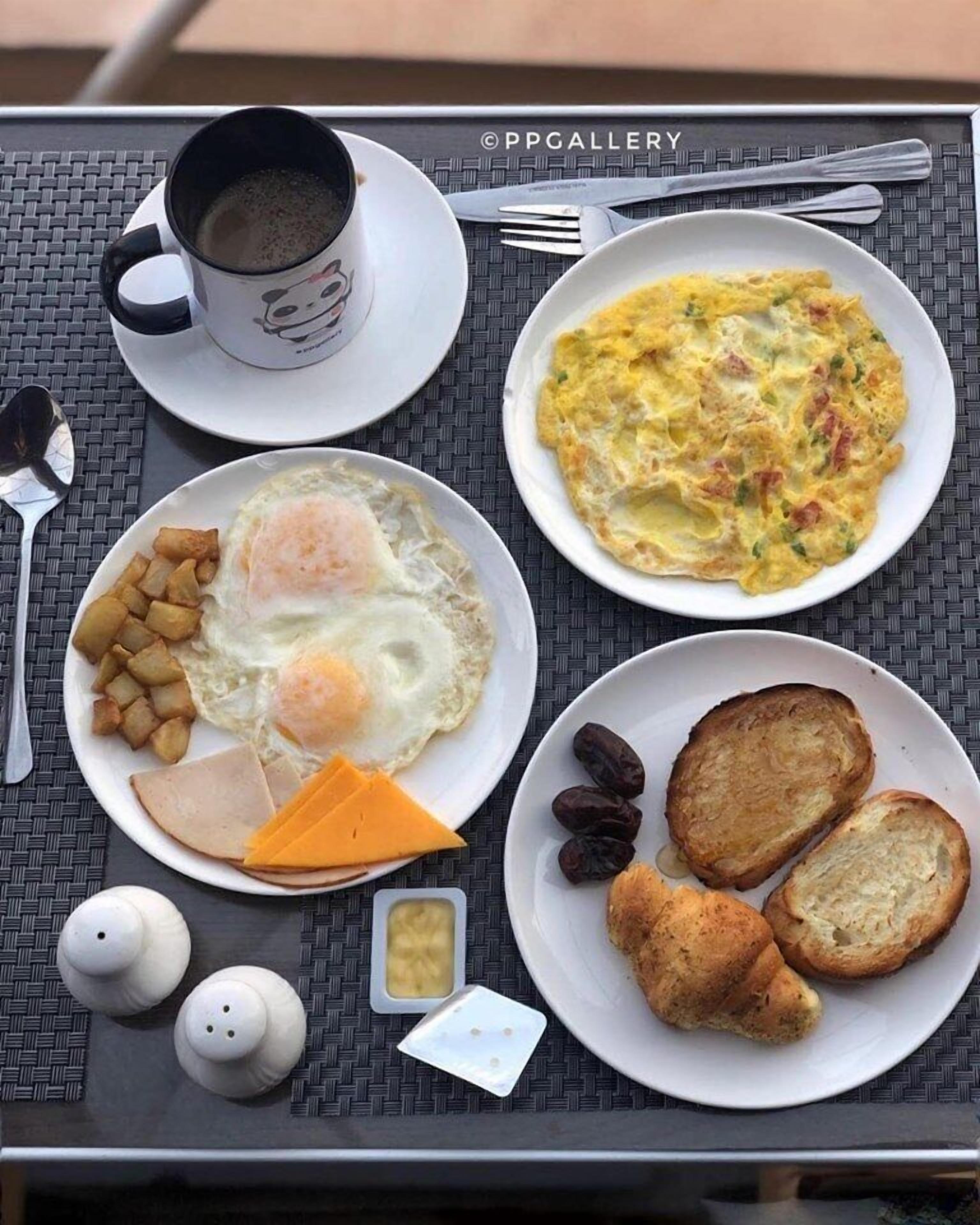 A breakfast tray with eggs, toast, ham, cheese, and a cup of coffee.