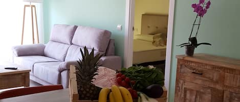 A dining area with a wooden table, red chairs, a fruit basket, and a wooden cabinet with drawers.