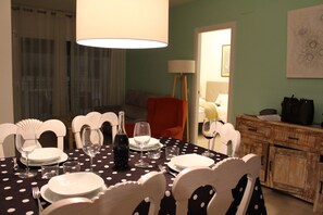 Ein Essbereich mit einem Tisch für vier Personen, Stühlen, einer Weinflasche und einer Lampe.