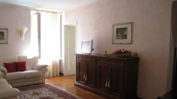 A living room with a sofa, a television on a cabinet, and a patterned rug. - Elisabetta Rapallo's house (Rapallo)