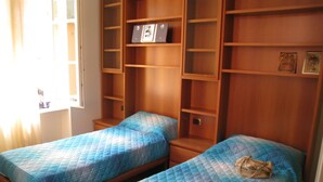 A room with two beds, wooden shelving, and a window. - Elisabetta Rapallo's house (Rapallo)