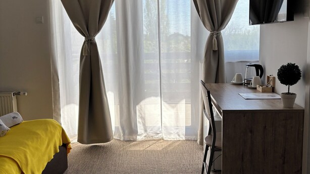 Hotellihuone, jossa on sänky, työpöytä, televisio ja näkymä ulos.