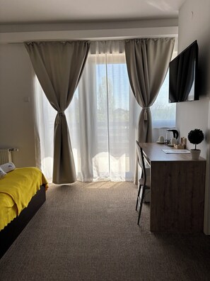 A hotel room with a bed, a desk, a TV, and a view of the outdoors. - London Rooms Zagreb Airport (Velika Gorica)