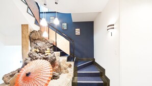 Una escalera con alfombra azul, un paraguas decorativo y una pared de piedra.