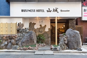 A business hotel entrance with a stone facade, large rocks, and a traditional Japanese gate. - Business Hotel Yamashiro (Tokyo)