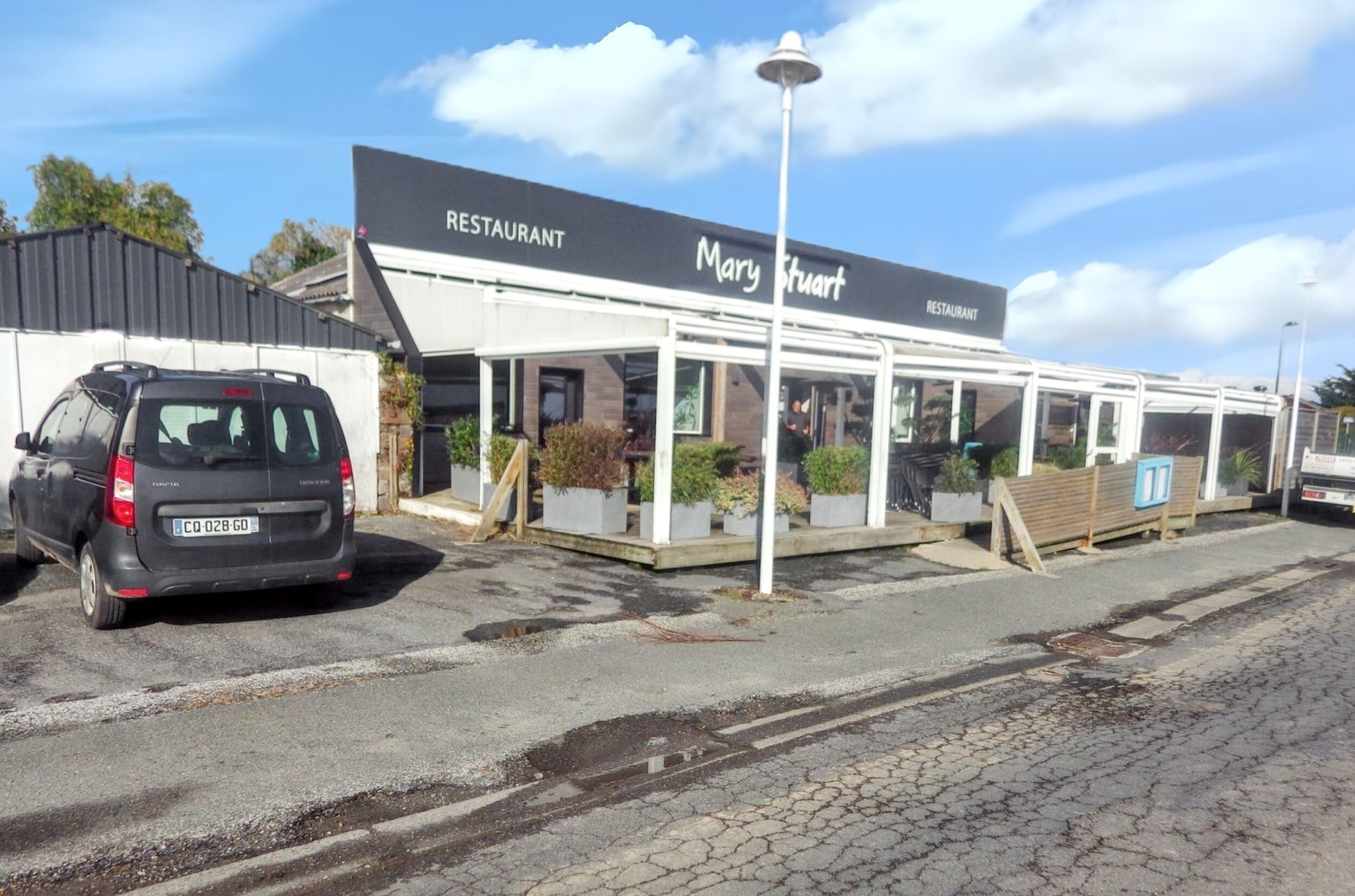 Un ristorante chiamato 'Mary Stuart' con una zona pranzo all'aperto coperta e un'auto parcheggiata.