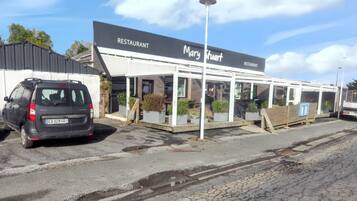 Un ristorante chiamato 'Mary Stuart' con una zona pranzo all'aperto coperta e un'auto parcheggiata.