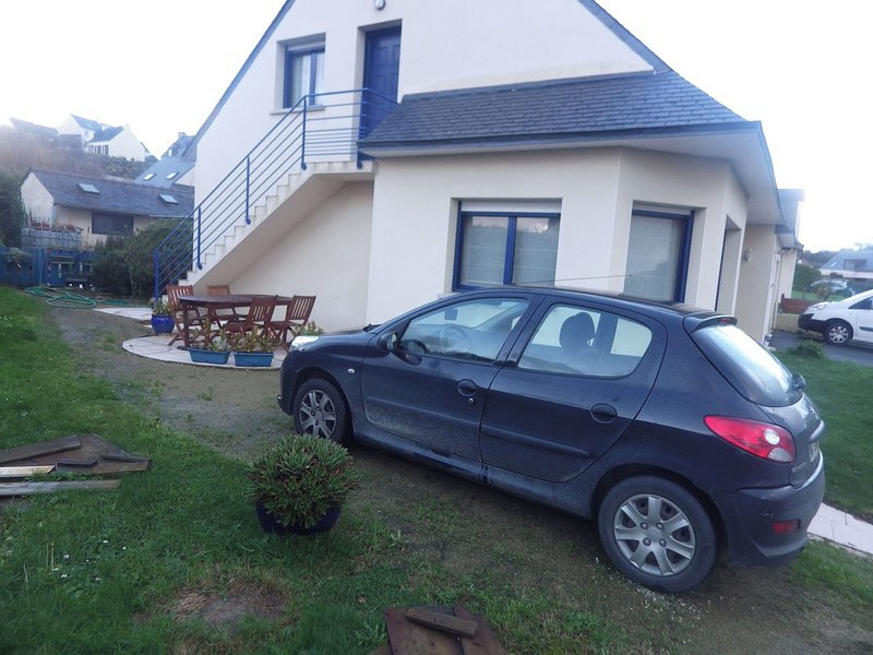 A two-story house with a car parked in the driveway.