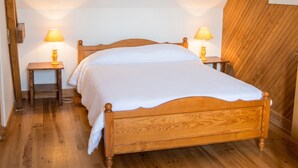 A wooden bed with white bedding, two bedside lamps, and a wooden floor. - Homerez - Villa in Issac (Issac)